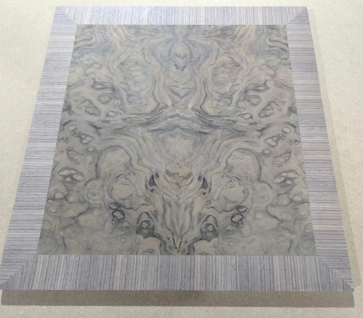 A custom cabinet panel on the shop floor: a book-matched walnut burl field framed by a border of straight-grained quartered walnut