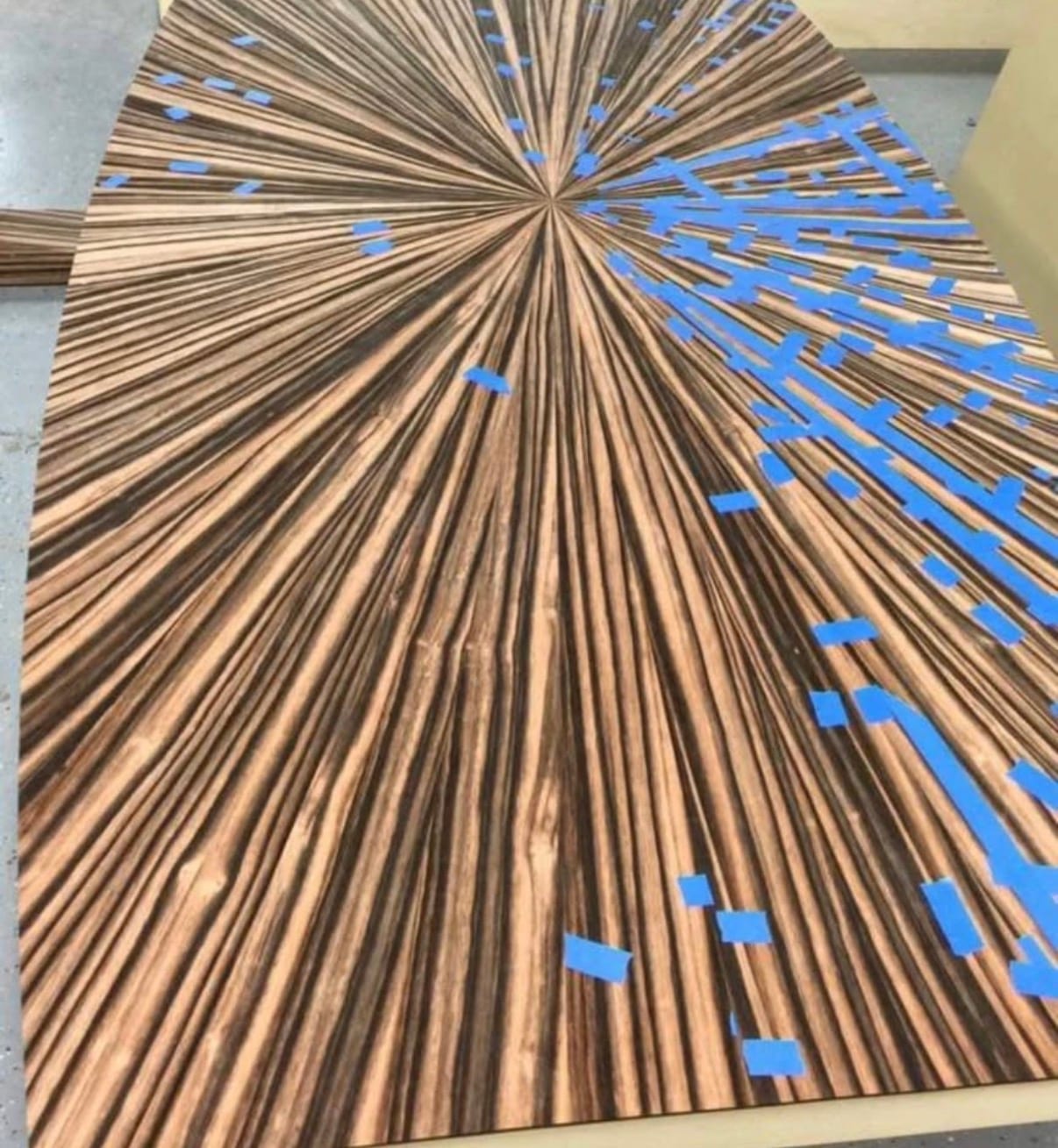 The same radial-matched ebony table top part-assembled on the bench, individual wedges of veneer laid out before pressing