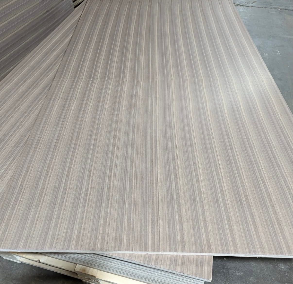 A large flip-matched quartered walnut panel on the shop floor, alternate leaves reversed so the grain mirrors across each seam