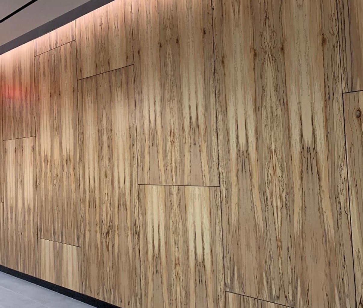 A wide wall panelled in spalted maple veneer, the dark spalting lines running vertically across sequenced panels