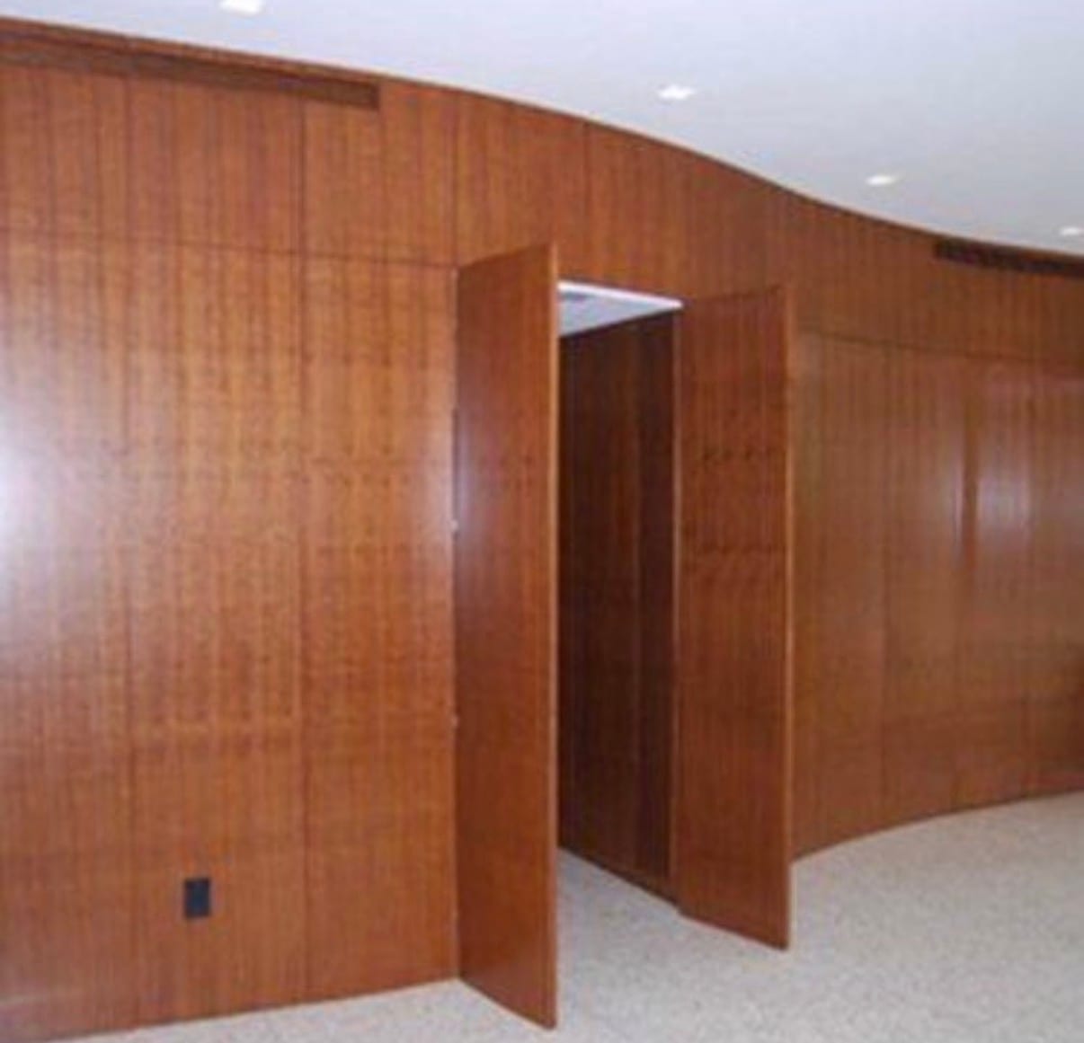 Curved radius walls faced in two-ply veneer with a fine vertical ribbon stripe, the flexible backer allowing a continuous bend around the curve